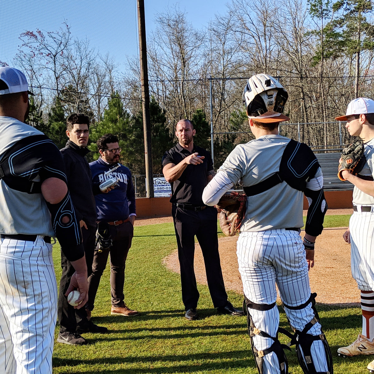 Jason Colleran on field with several baseball players that are wearing the Kinetic Arm explaining significance of dual joint support