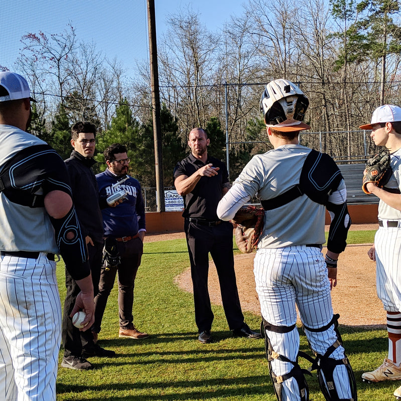 Jason Colleran on field with several baseball players that are wearing the Kinetic Arm explaining significance of dual joint support